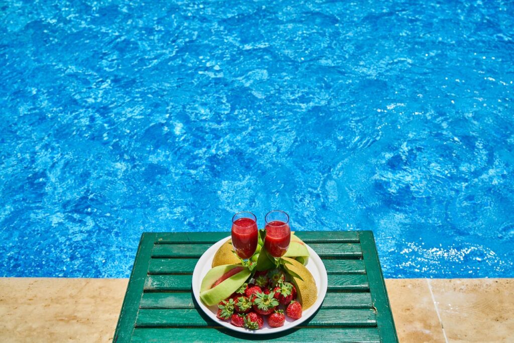 Two refreshing fruit drinks with strawberries by a pool, offering a vibrant summer vibe.